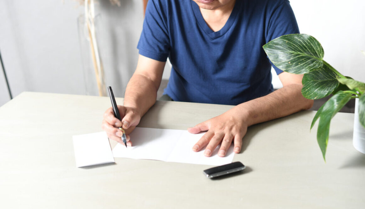 Hand of an elderly Asian man writing a sentence