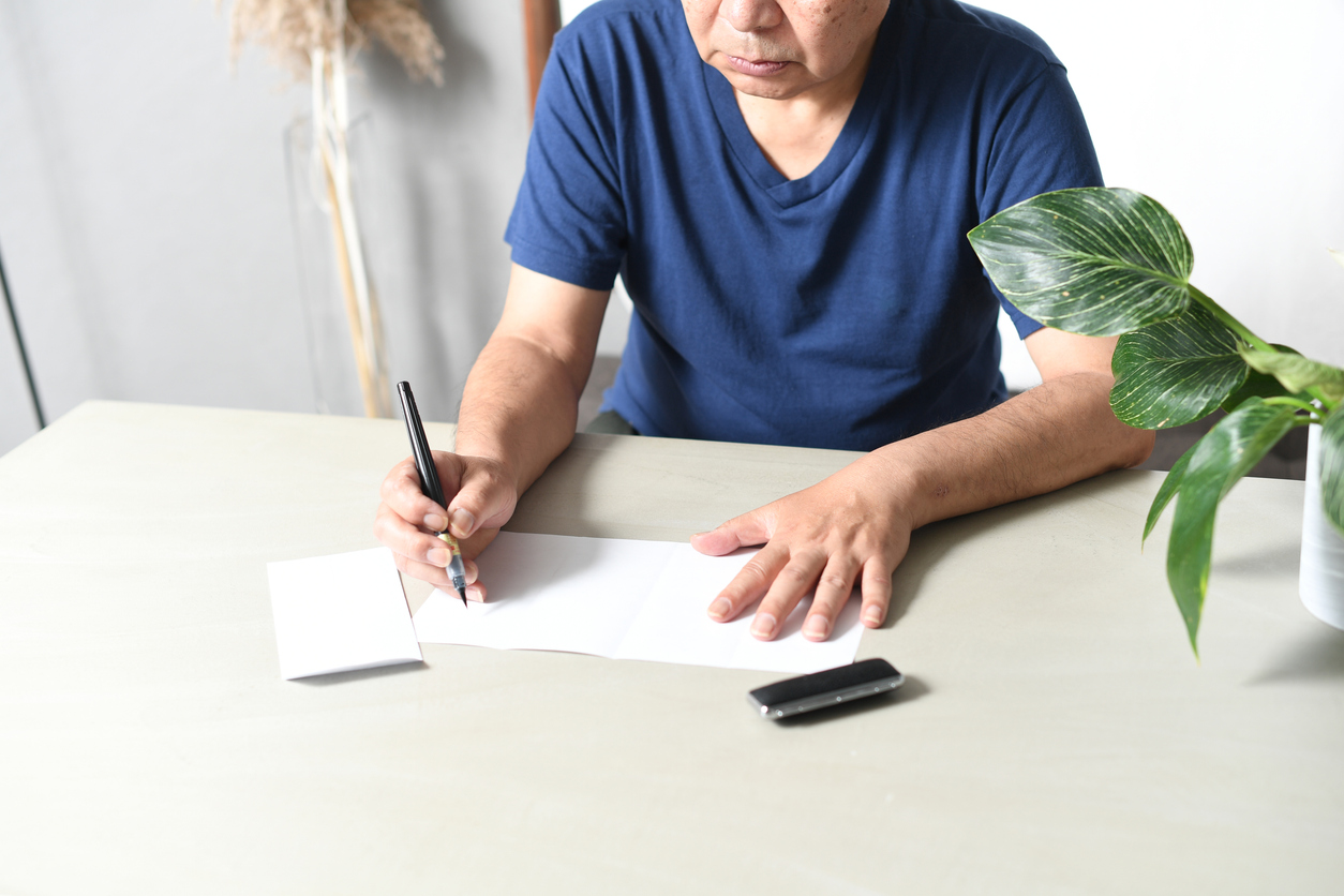 Hand of an elderly Asian man writing a sentence